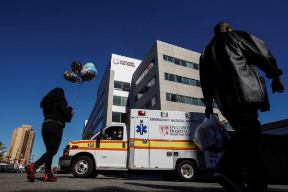 People walk near the University Hospital where a nurse is being held in isolation for Ebola symptoms in Newark, New Jersey