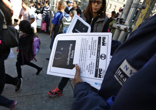 New York City Health department official hands out information on the Ebola virus outside a school near a Bronx New York apartment building, from where a 5-year-old boy who arrived from Guinea was taken to Bellevue Hospital in New York