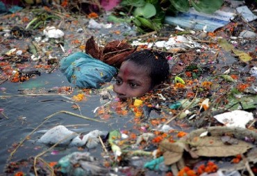 epa00832196 Indian local boy wade through the pollution and floating debris left after the immersion of hundreds of idols of Hindu goddess Durga into the River Yamuna in New Delhi, India Monday 02 October 2006. The Hindu Festival of Durga Puja, celebrates the killing of a demon king by the goddess ended today with colourful celebrations all over the country. Every autumn, Bengalis all over the world celebrate her festival which not only represents the victory of good over evil, but is also a celebration of female power.  EPA/HARISH TYAGI