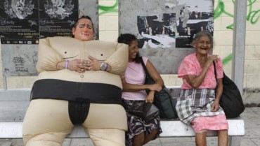 FILE - In this May 15, 2012 file photo, a clown jokes as he sits at a bus stop during a clown parade in San Salvador, El Salvador. A poll released Wednesday of nearly 150,000 people around the world says seven of the world's 10 countries with the most upbeat attitudes are in Latin America. In Panama and Paraguay, 85 percent of those polled said yes to all five, putting those countries at the top of the list. They were followed closely by El Salvador, Venezuela, Trinidad and Tobago, Thailand, Guatemala, the Philippines, Ecuador and Costa Rica. (AP Photo/Luis Romero, File)