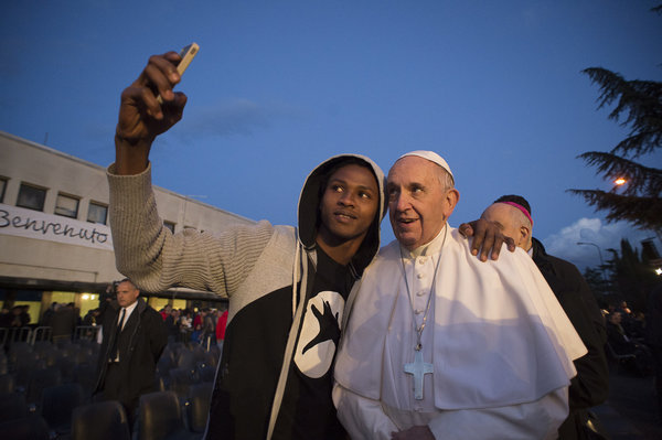 Pope Francis poses for a selfie during his visit at the Castelnuovo di Porto refugees center, some 30km (18, 6 miles) from Rome, Thursday, March 24, 2016. The pontiff washed and kissed the feet of Muslim, Orthodox, Hindu and Catholic refugees Thursday, declaring them children of the same God, in a gesture of welcome and brotherhood at a time when anti-Muslim and anti-immigrant sentiment has spiked following the Brussels attacks. (L'Osservatore Romano/Pool Photo via AP)
