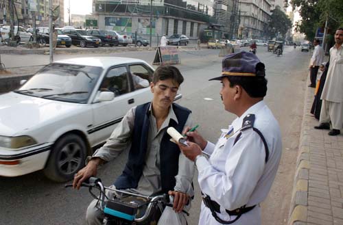 KARACHI, PAKISTAN, JAN 17: A traffic police officer does Challan of a motorcyclist, who was without helmet, at II.Chandrigar road in Karachi on Tuesday, January 17, 2012. (Rizwan Ali/PPI Images).